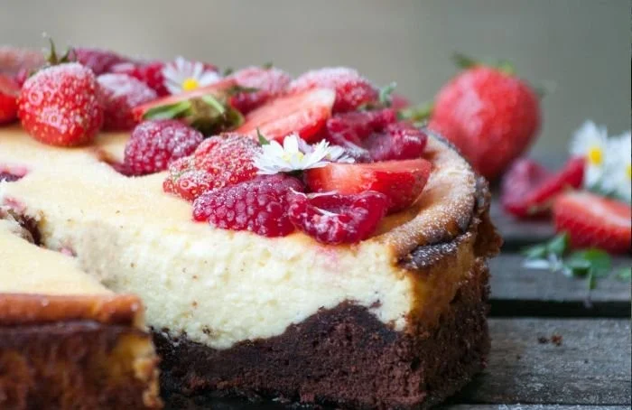 Brownie-Käsekuchen mit Himbeeren und Erdbeeren auf einem weißen Teller