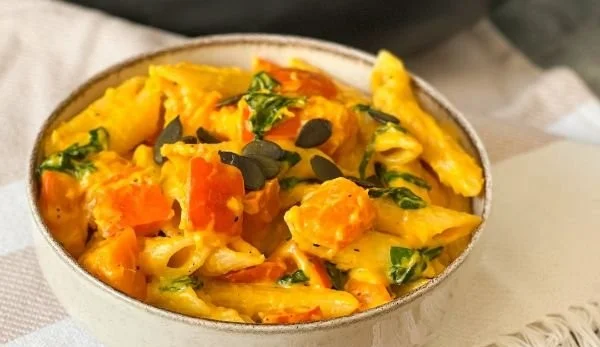 Kürbis-Pasta mit Spinat auf einem Teller serviert.