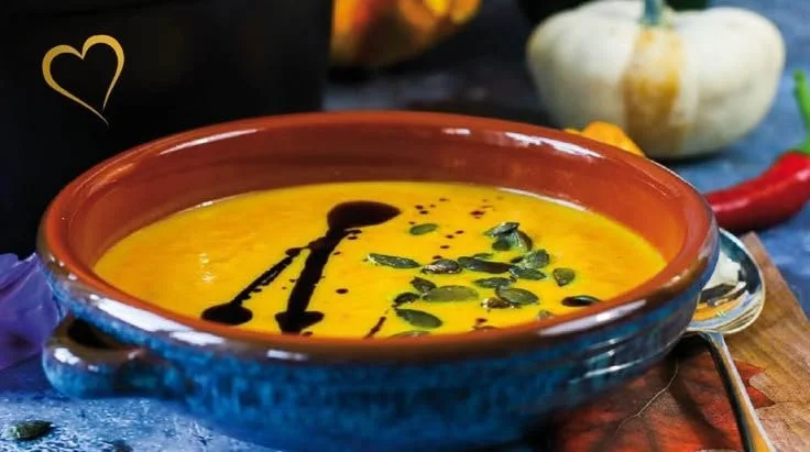 Kürbissuppe mit Curry in einer Schüssel garniert mit frischen Kräutern