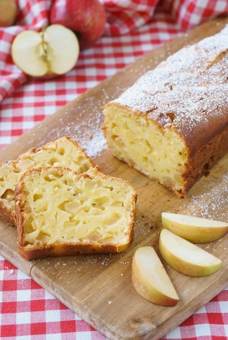Ein Stück saftiger Apfelkuchen auf einem Teller, dekoriert mit Zimt und Äpfeln.