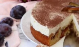 Saftiger Zwetschgenkuchen mit Sahne-Schmand-Haube auf einem Teller serviert.